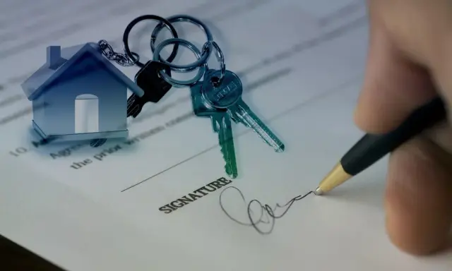 Clés d'une maison sur un contrat, symbolisant un prêt consommation pour achat immobilier. Signature apposée.