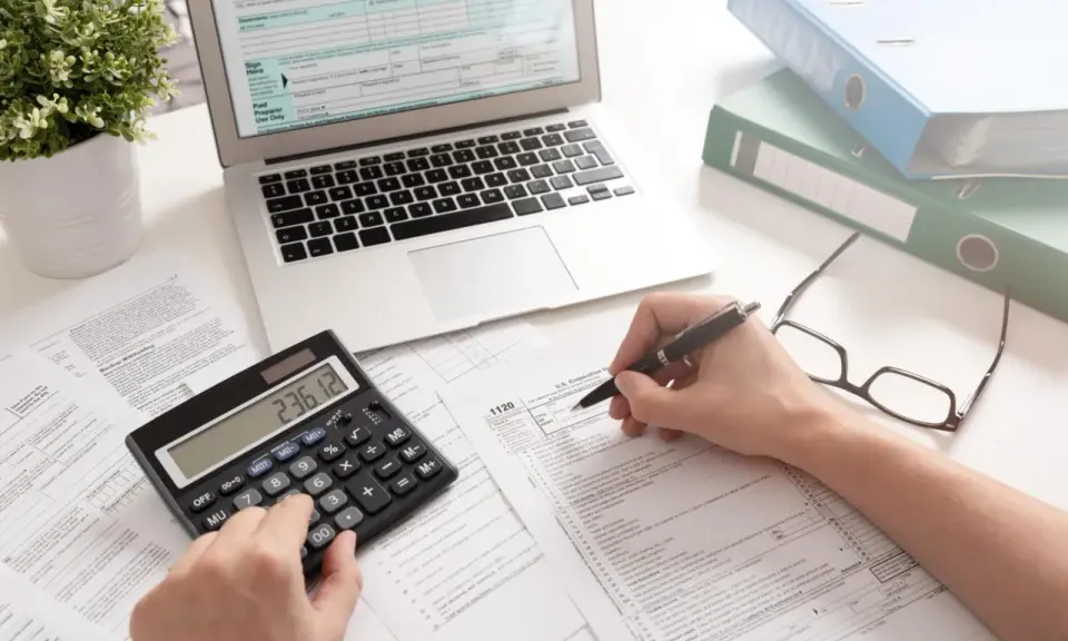 Calculatrice, ordinateur et formulaires fiscaux. On y voit des calculs pour déterminer quels sont les intérêts d'emprunt déductibles.