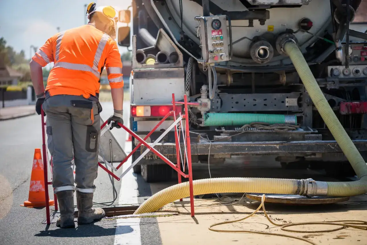 Un ouvrier en tenue de s&eacute;curit&eacute; effectue la vidange d'une fosse septique, une &eacute;tape n&eacute;cessaire avant le d&eacute;part d'un locataire.