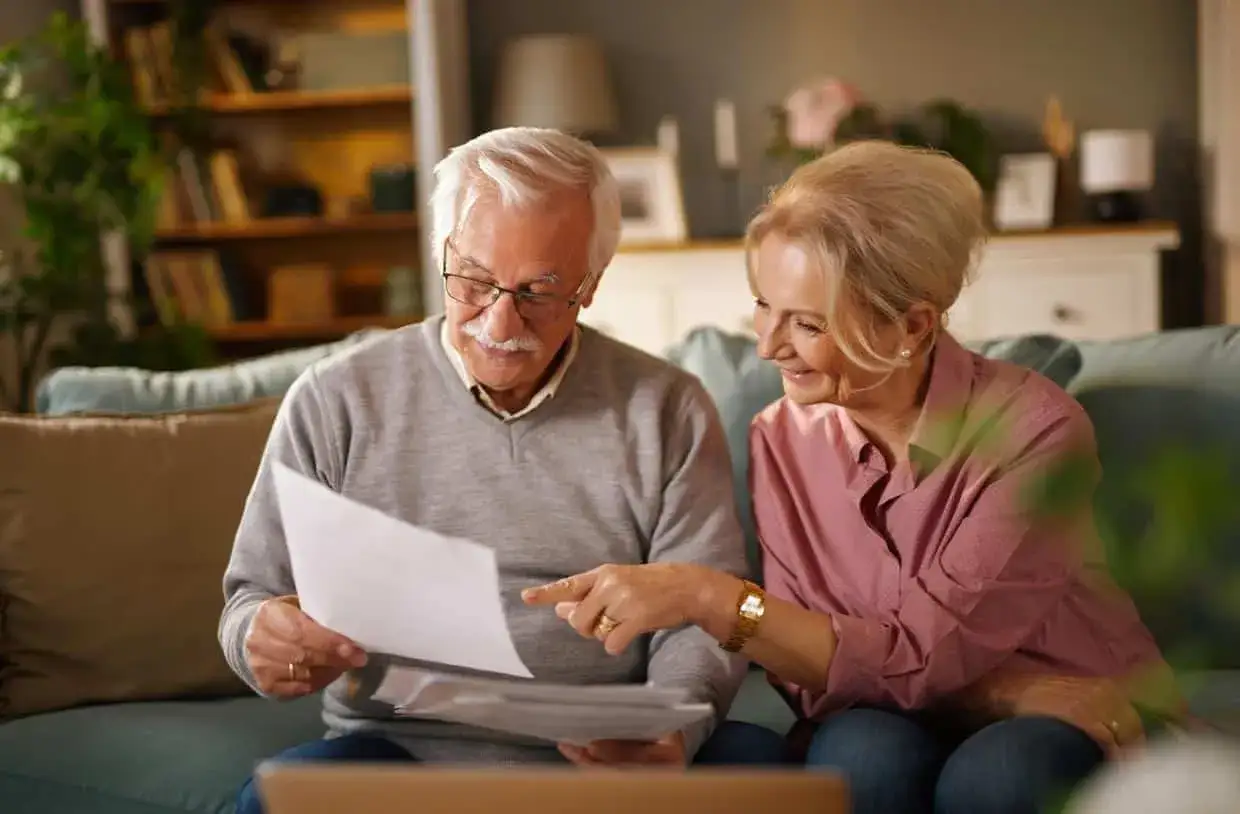 Couple âgé discutant de documents, envisageant une simulation prêt immobilier après 60 ans.