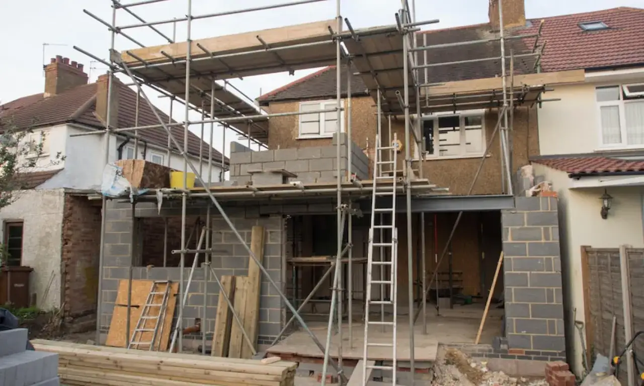 Chantier de construction avec &eacute;chafaudages, ma&ccedil;onnerie en cours. Ces travaux sur parties communes sans autorisation semblent modifier l'aspect de la maison.