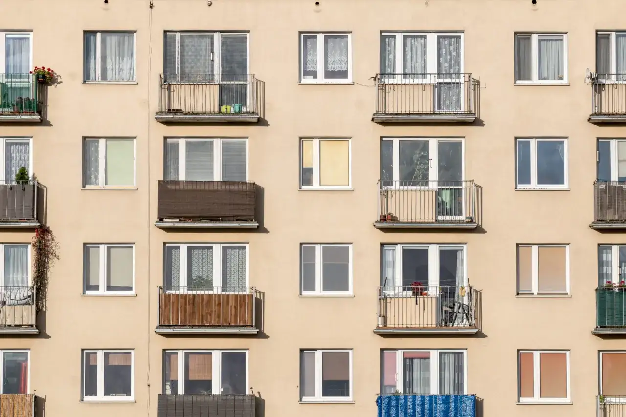 Fa&ccedil;ade d'immeuble avec de nombreuses fen&ecirc;tres et balcons. L'aspect h&eacute;t&eacute;rog&egrave;ne sugg&egrave;re une r&eacute;novation, peut-&ecirc;tre une obligation propri&eacute;taire changer fen&ecirc;tres.