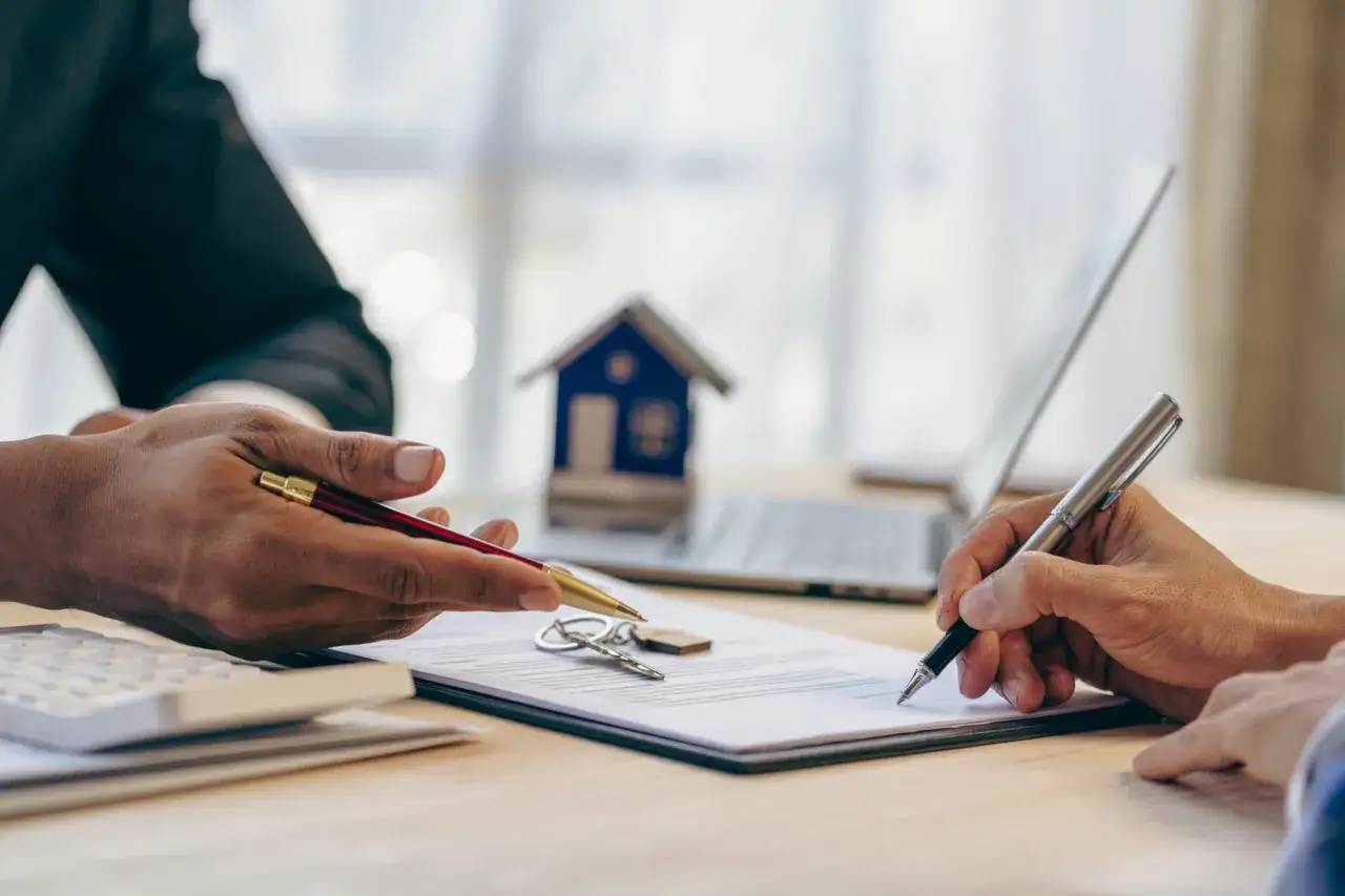 Signature d'un pr&ecirc;t immobilier. Quel salaire pour emprunter 200 000 euros ? Cl&eacute;s, maison mod&egrave;le et calculatrice sur le bureau.