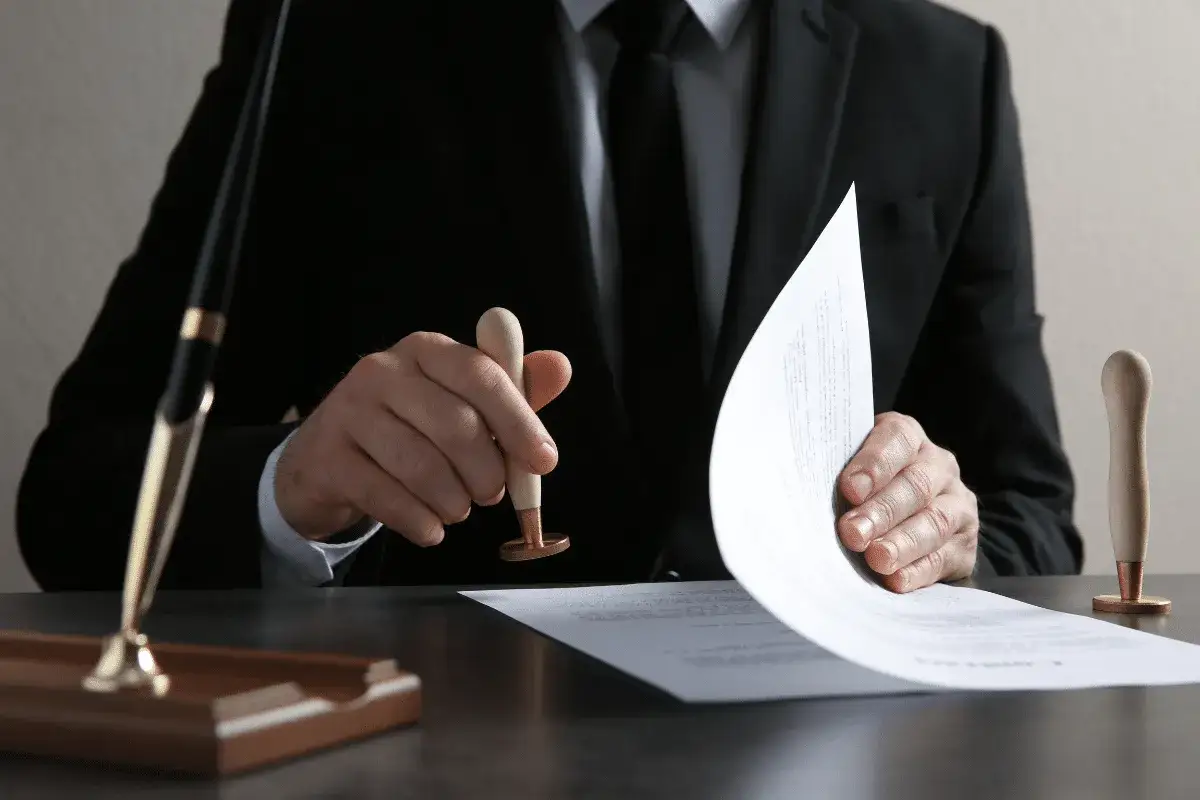 Un homme en costume appose un sceau sur un document, &eacute;tape cl&eacute; pour savoir comment obtenir un titre de propri&eacute;t&eacute;.