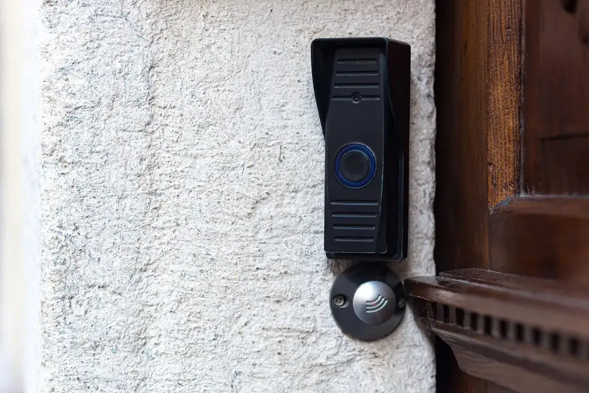 Sonnette moderne sur mur textur&eacute;, pr&egrave;s d'une porte en bois. Id&eacute;al pour la r&eacute;paration sonnette locataire ou propri&eacute;taire.