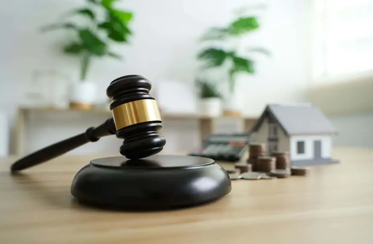 Marteau de juge, maison miniature, calculatrice et pi&egrave;ces. Le d&eacute;lai de paiement apr&egrave;s signature de l'acte de vente est crucial.